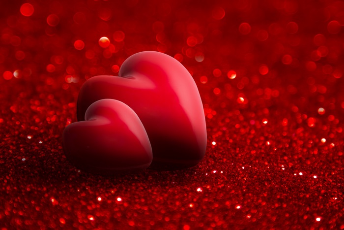 Two red hearts on a red glitter background