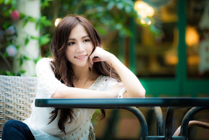 Asian woman sitting at a table outdoors