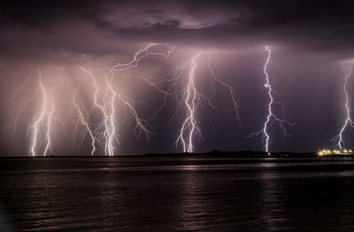 Lightning strikes over the ocean at night