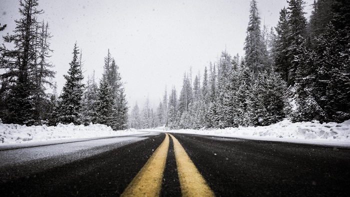 Road through snowy forest in 4K