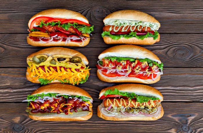Six gourmet hot dogs on a wooden table