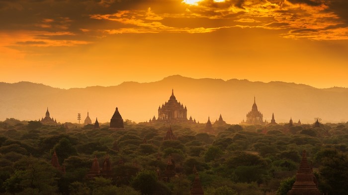 Temples in Bagan at sunset with mountains and clouds