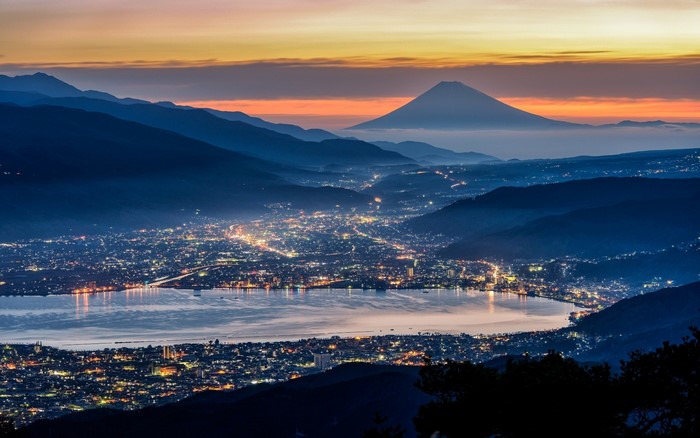Mount Fuji and city lights at dusk over a lake