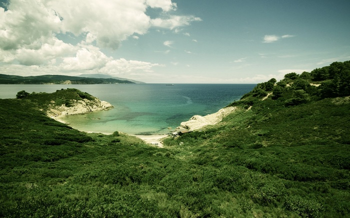 Green hills overlooking a bay with turquoise water
