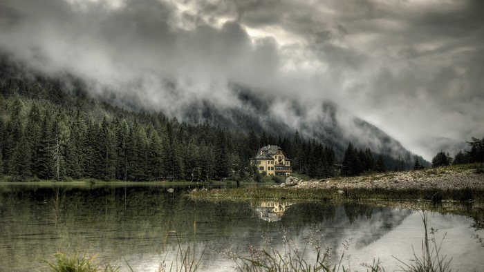 House by a misty mountain lake and forest