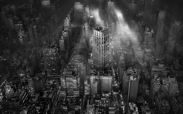 Monochrome aerial view of New York City skyscrapers at night with light beams
