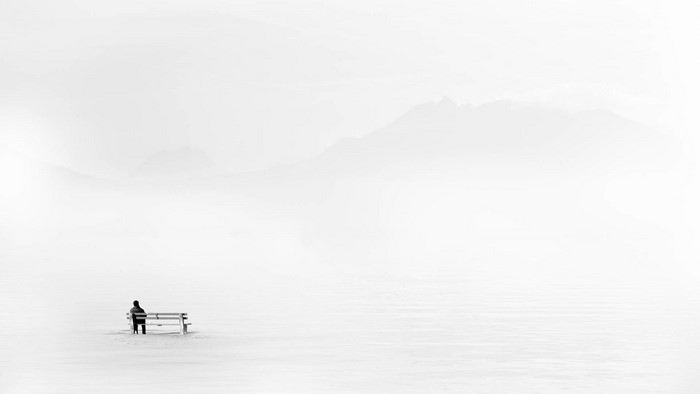 Man sitting on a bench in a snowy landscape with mountains