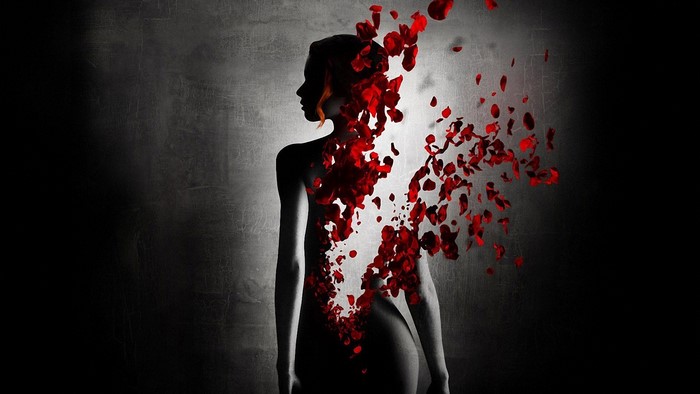 Woman dissolving into red rose petals