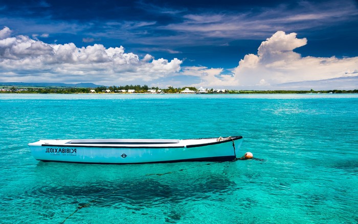 Boat on turquoise water with Mauritius island in background