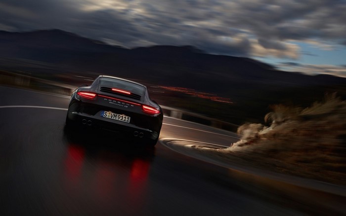 Black Porsche 911 Carrera 4S driving on a winding road