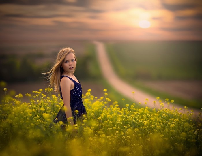 Girl in yellow flowers with path and sunset