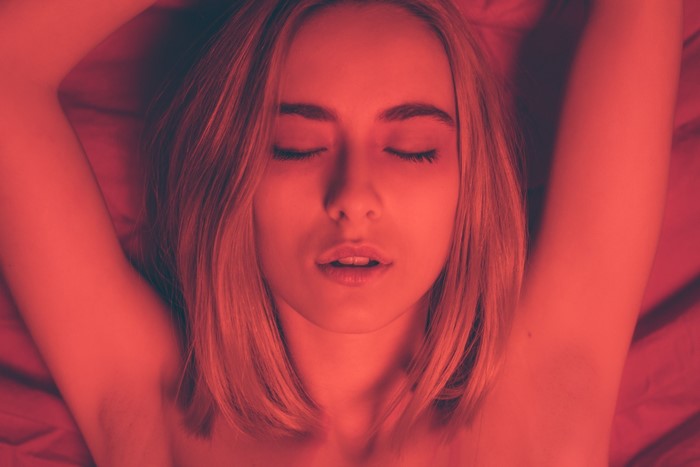 Woman with blonde hair lying down with arms raised