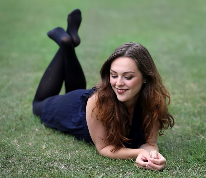 Woman in dark blue dress and pantyhose lying on grass