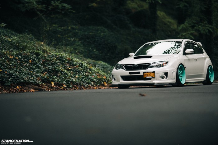 White Subaru Impreza on a road with trees