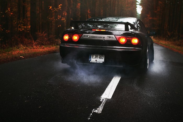Nissan 180SX performing a burnout on a forest road