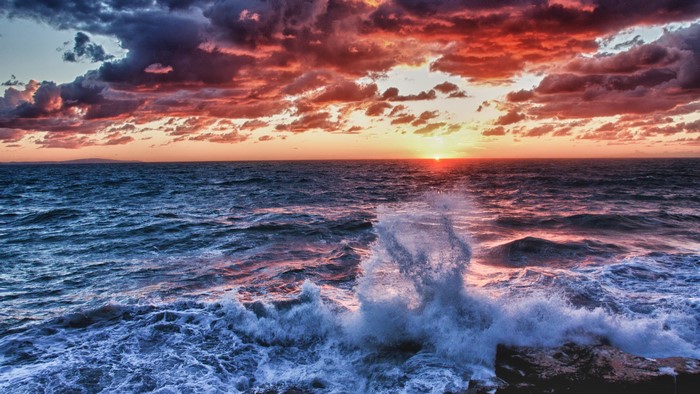 Sunset over the ocean with crashing waves