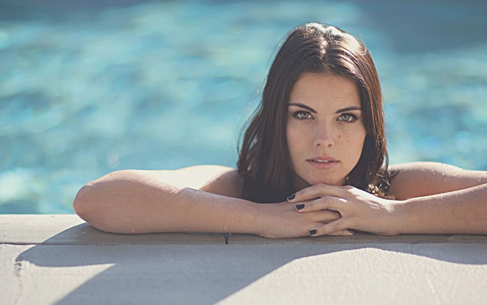 Woman with wet hair leaning on pool edge