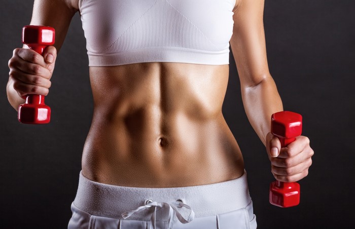 Woman with toned abs holding dumbbells