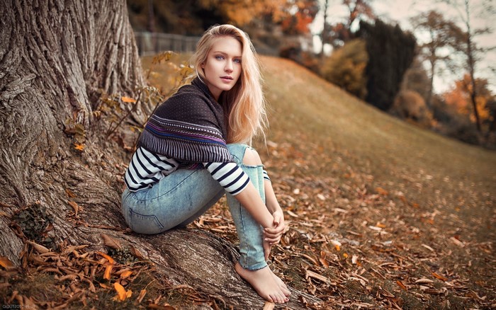 Woman with blonde hair sitting by a tree