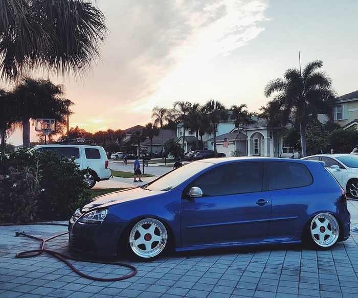 Blue Volkswagen Golf MK5 lowered on custom wheels at sunset
