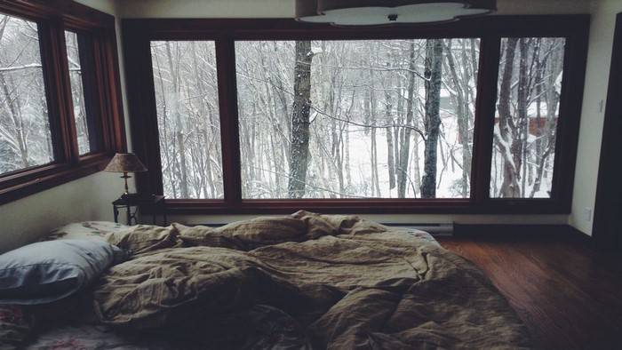 Bedroom with a large window overlooking a snowy forest