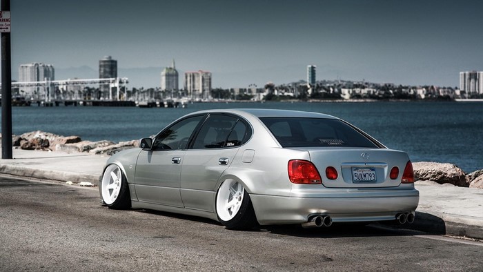 Silver Lexus GS with white wheels parked by the water