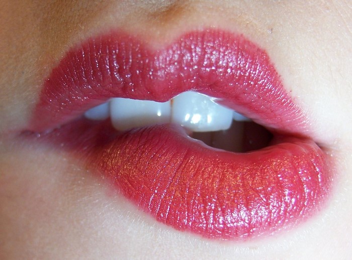Close-up of red lipstick on lips biting lip