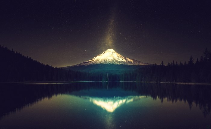 Snowy mountain at night reflected in a lake