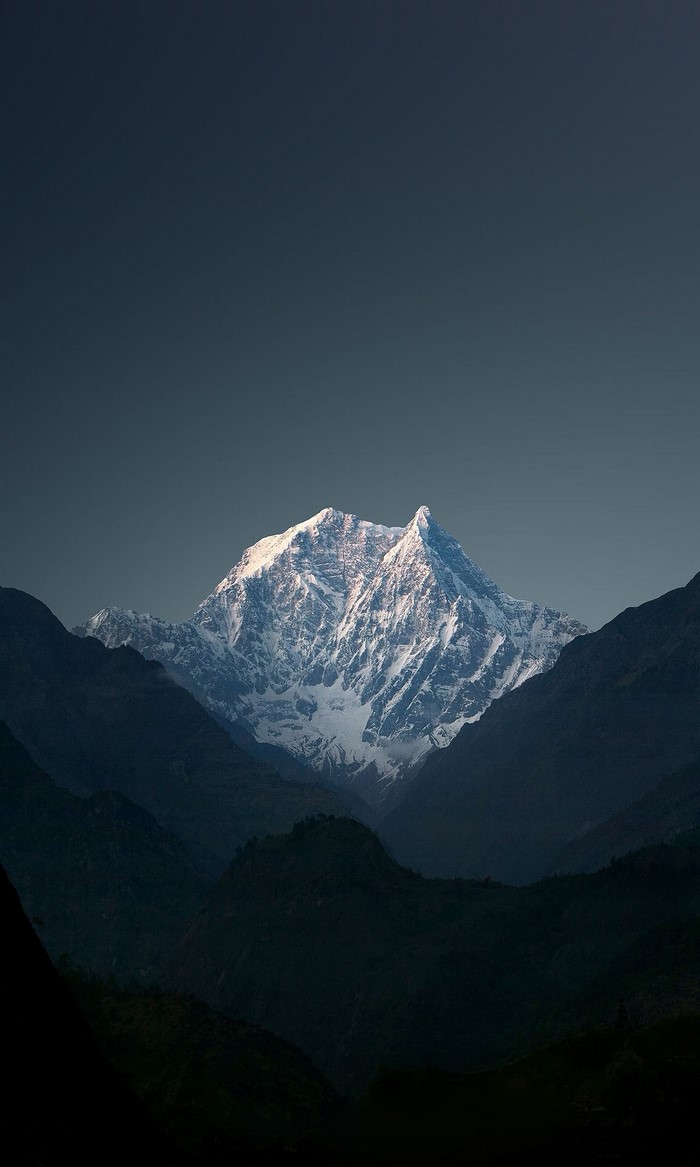 Snow-capped mountain peak against a dark sky