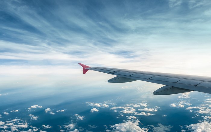 Airplane wing flying over clouds in the sky