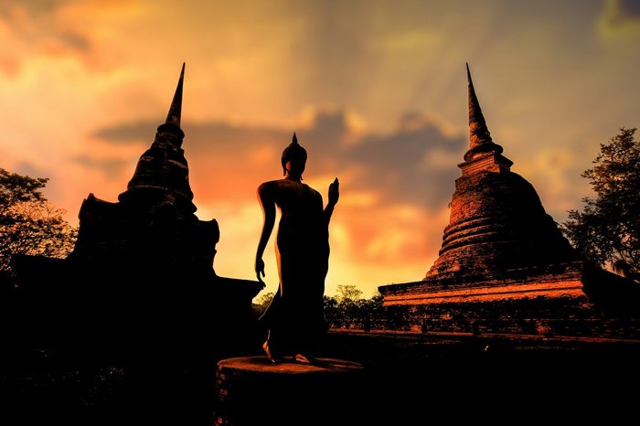 Buddha statue and stupas at sunset in Thailand