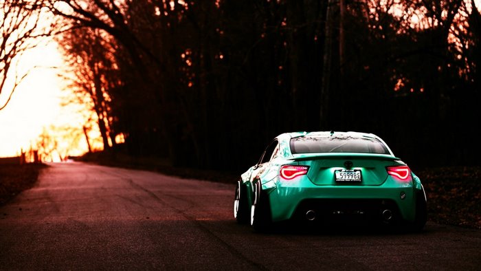 Green Toyota GT86 with wide body kit on a road
