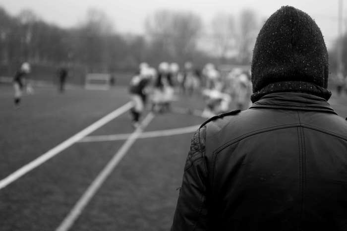 Person in black jacket watching a football game