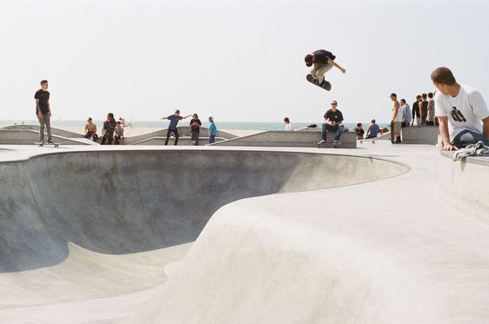 Skateboarder jumps in the air at a skatepark by the beach