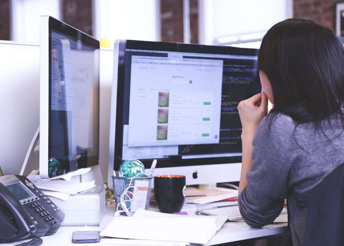 Woman working on Apple iMac computers in an office