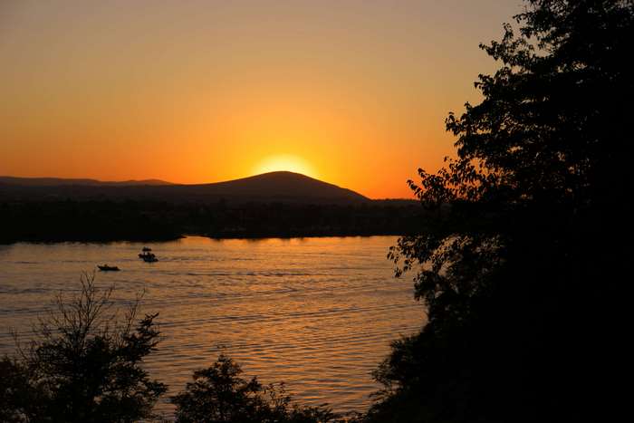 Sunset over a river with boats and trees