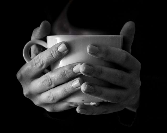 Hands holding a steaming cup of coffee or tea