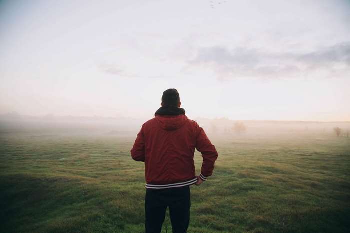 Man in red jacket in foggy field