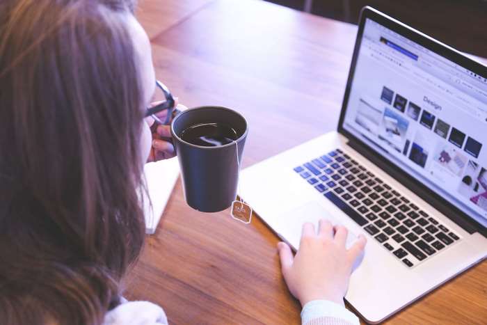 Woman drinking tea while working on a laptop