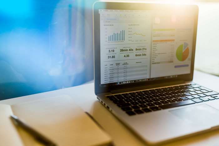 Laptop with financial charts and notebook