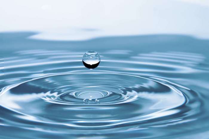 Water drop creating ripples on a liquid surface