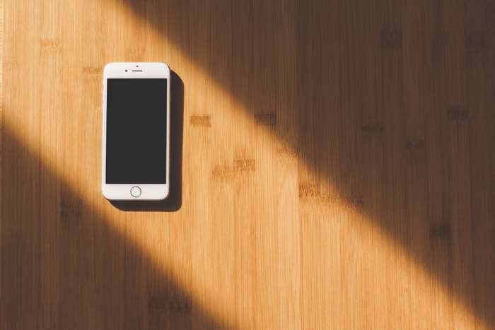 White iPhone on a wooden table with sunlight