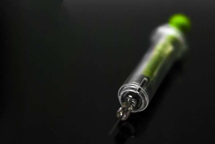 Close up of a syringe with green liquid