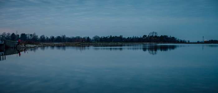 Calm reservoir with trees and sky reflection