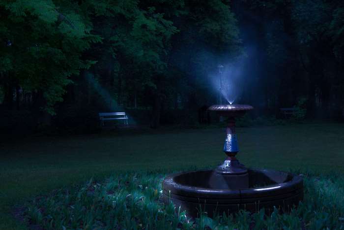 Blue fountain in a park at night