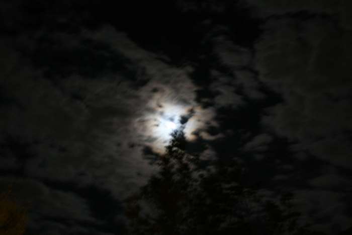 Moon behind dark clouds at night