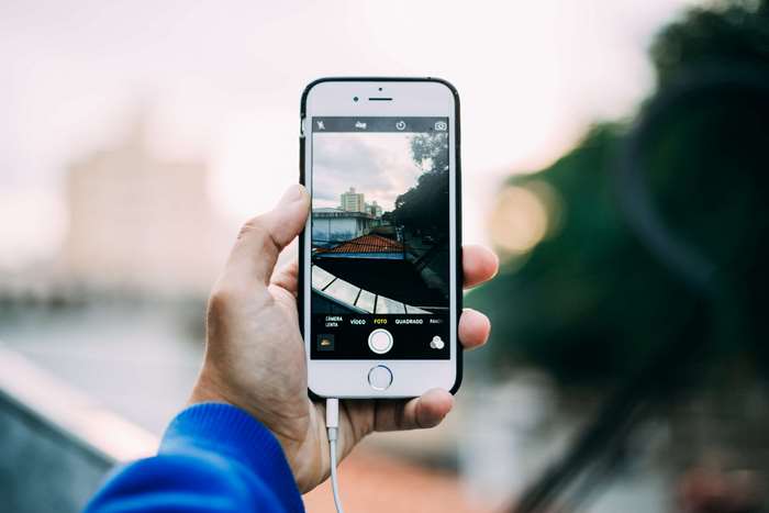 Hand holding iPhone taking a picture of buildings