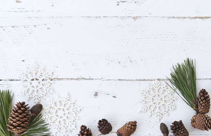 Winter holiday flatlay with pine cones and snowflakes on white wood