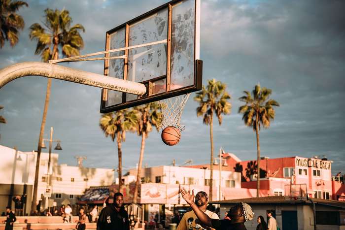 Basketball game on Venice Beach with palm trees and buildings
