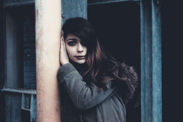 Young woman leaning against a pole